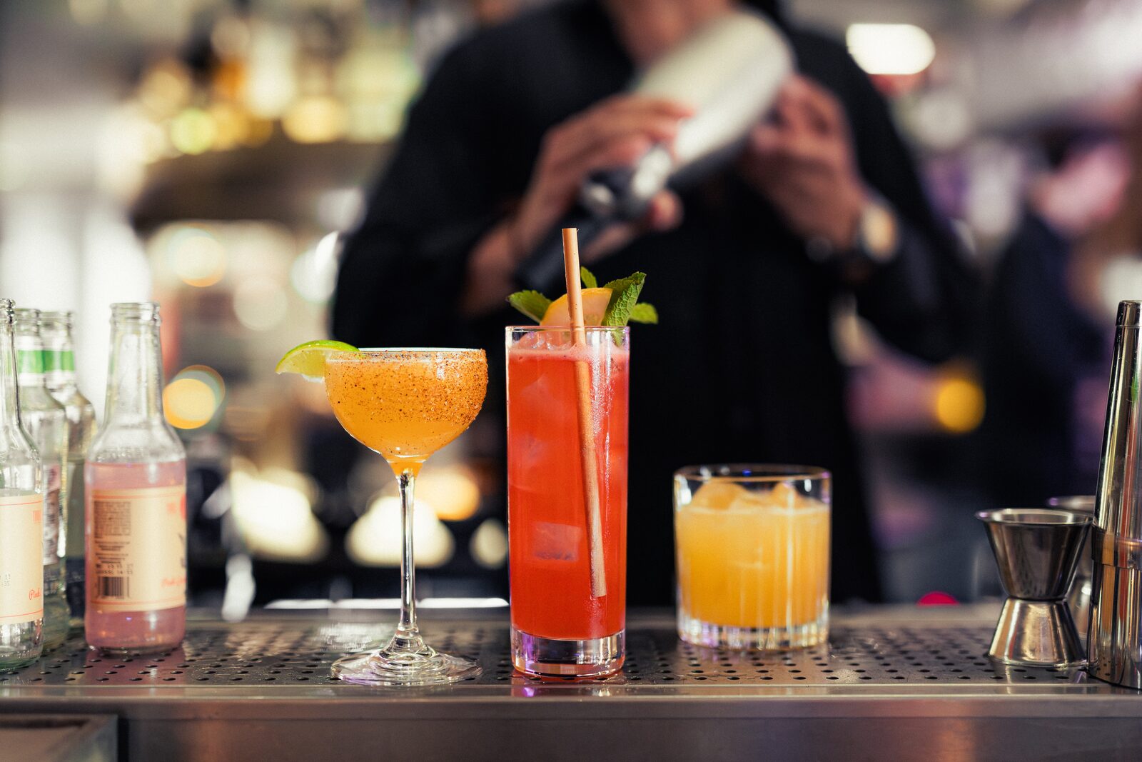 Tre cocktails uppradade framför barens sortiment